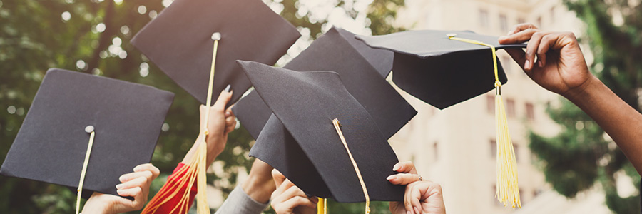 image of hands holding up graduation caps